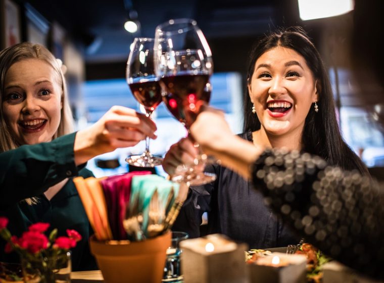 Iloiset ravintola-asiakkaat kohottavat maljaa ravintolassa.